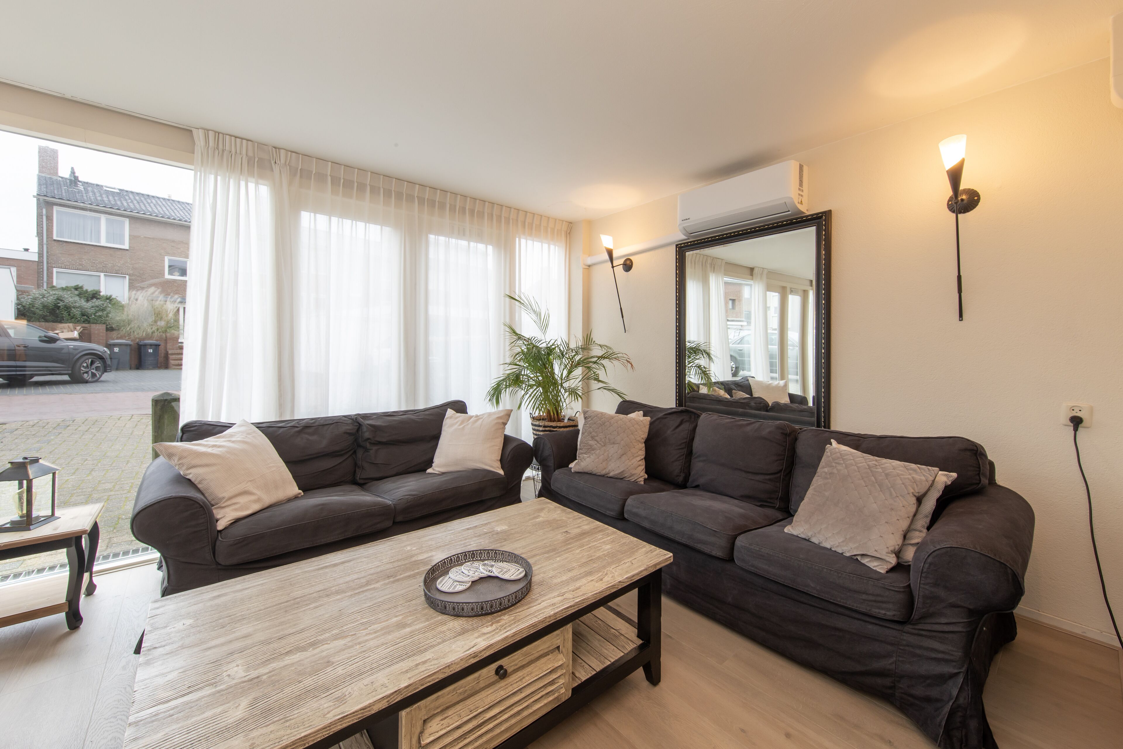 A modern living room with two dark sofas, a wooden coffee table, and a large mirror.