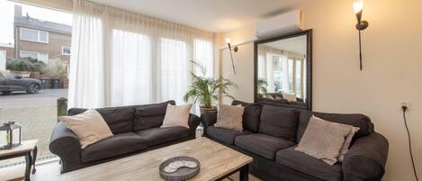 A modern living room with two dark sofas, a wooden coffee table, and a large mirror.