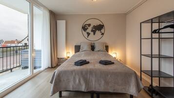 A bedroom with a large bed, a world map on the wall, a wardrobe, and a view of the outside.