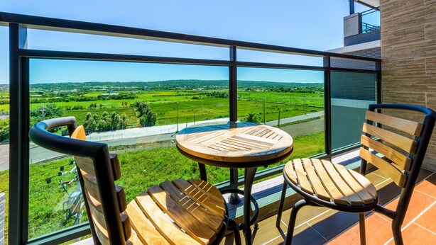 Un balcon avec une table et deux chaises, offrant une vue sur un paysage verdoyant.