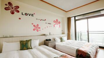 Une chambre d’hôtel avec deux lits, une grande fenêtre et une décoration murale portant l’inscription : « L’amour est une fleur qui s’épanouit ».