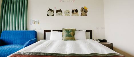 Een hotelkamer met een bed, een blauwe bank, een groen gordijn, een muur met katteposters en een kussen met een groen patroon.