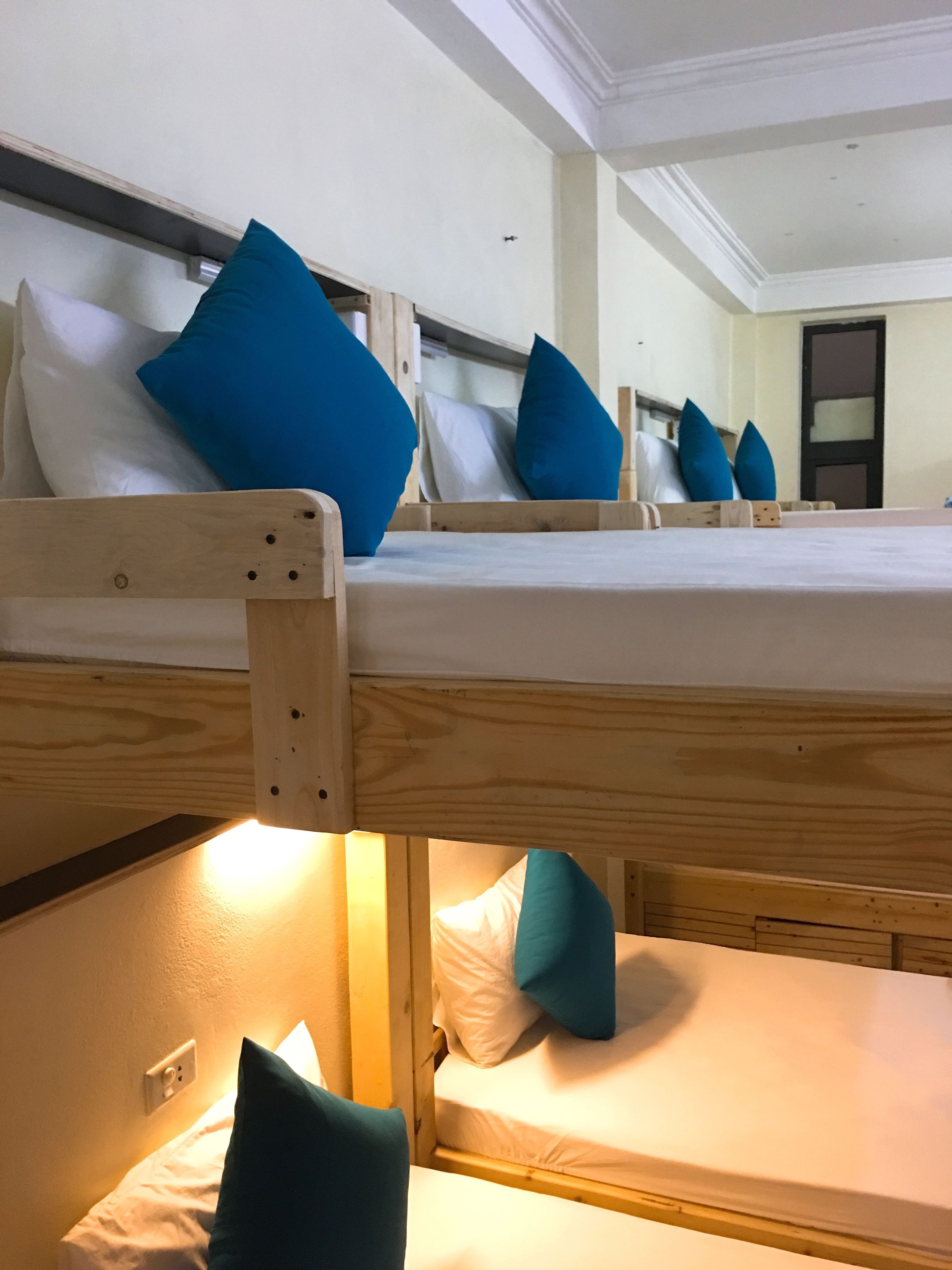A room with bunk beds, each with pillows and a mattress.