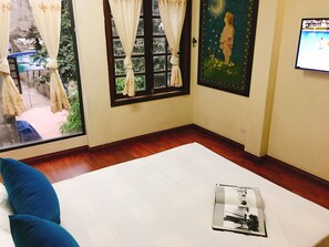 A room with a large window, a bed with blue pillows, a framed picture on the wall, and a TV screen displaying a sports event. - Halo Bay Homestay (Hon Gai)