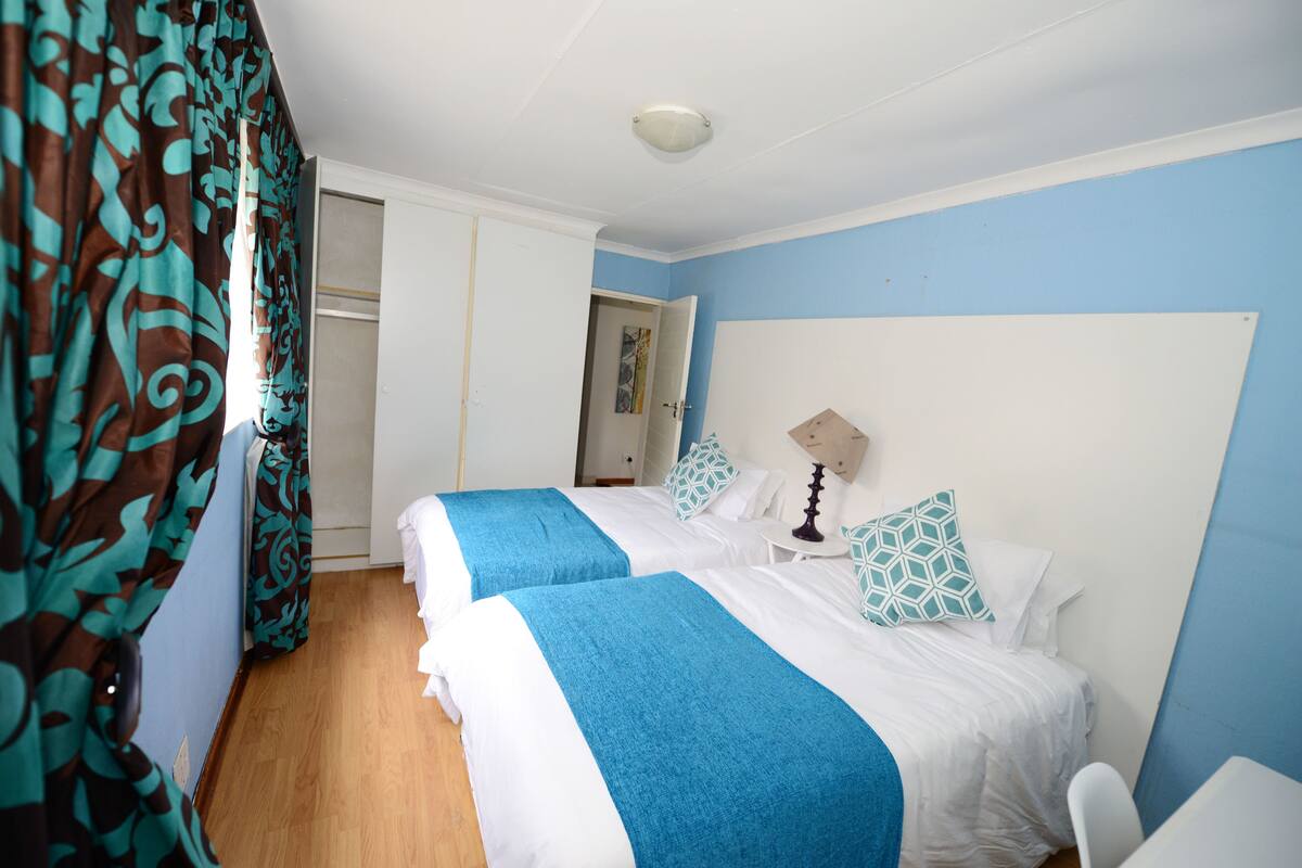 Una habitación de hotel con dos camas, techo blanco y pared azul.