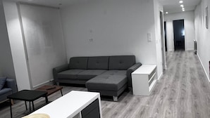 A modern living room with a grey sectional sofa, a white console table, and a wooden coffee table. - Hostal Mónaco (Valladolid)