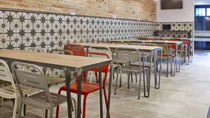 Interior de un restaurante con paredes de ladrillo, salpicadero de azulejos y varias mesas y sillas.
