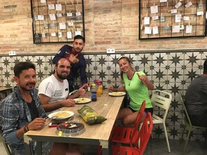 A group of people dining at a restaurant with a brick wall and star-patterned tiles. - Hola Hostal Collblanc - Hostel (L'Hospitalet de Llobregat)