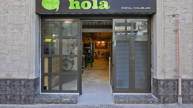 Entrada de un hotel con un cartel que dice 'hola', una puerta de cristal y una bicicleta estacionada en el interior.