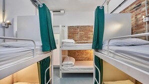 Un dormitorio con literas, pared de ladrillo y ventilador de techo.