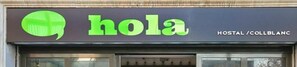 A hotel sign with the name 'hola' and 'HOSTAL /COLBLANC' indicating the establishment is a hostel. - Hola Hostal Collblanc - Hostel (L'Hospitalet de Llobregat)