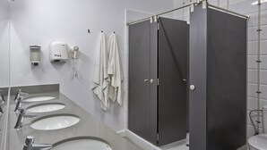 Un baño moderno con tres lavamanos, un secador de manos y un inodoro.