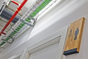 A wall-mounted sign indicating a men's restroom, a red pipe, and a green ventilation system. - Hola Hostal Collblanc - Hostel (L'Hospitalet de Llobregat)