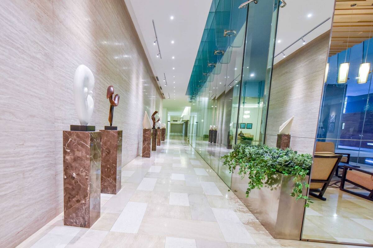 A modern hallway with marble columns, glass walls, and a plant.