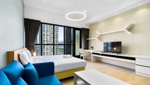 Ein modernes Hotelzimmer mit Bett, blauem Sofa, weißem Schreibtisch und einem Fernseher.