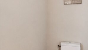 A small, narrow bathroom with a white toilet, a wooden floor, and a single framed picture on the wall. -  Maison de Maître Gentil'Home - 1699 (Fenouillet)