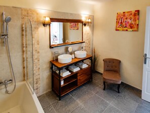A bathroom with a bathtub, two sinks, a vanity, and a chair. - Maison de Maître Gentil'Home - 1699 (Fenouillet)