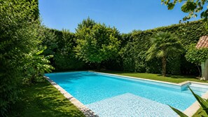 A rectangular swimming pool with a clear blue water surface, surrounded by lush green trees and grass. -  Maison de Maître Gentil'Home - 1699 (Fenouillet)