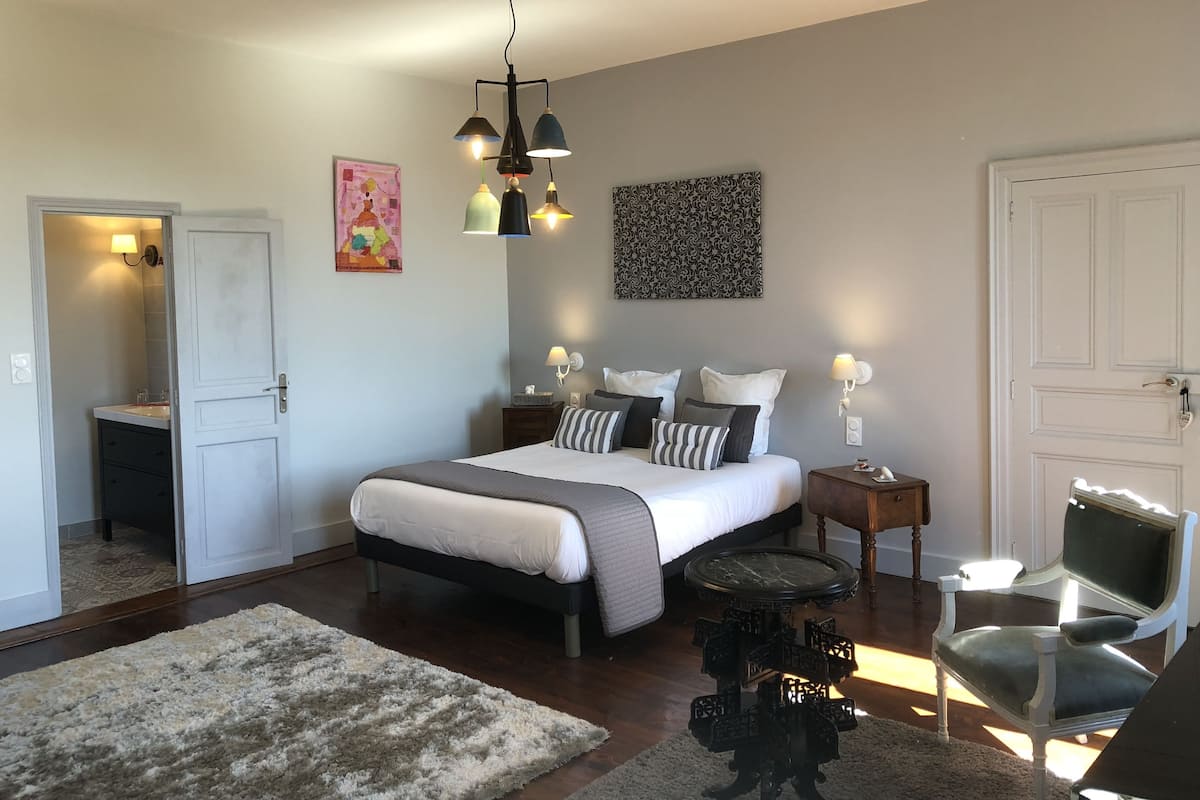 A bedroom with a bed, bedside tables, a chair, a rug, and artwork on the walls.
