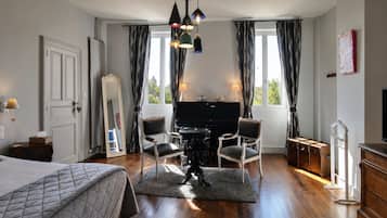 Un dormitorio con una cama, un piano, dos sillas, un espejo, un aparador y una televisión.