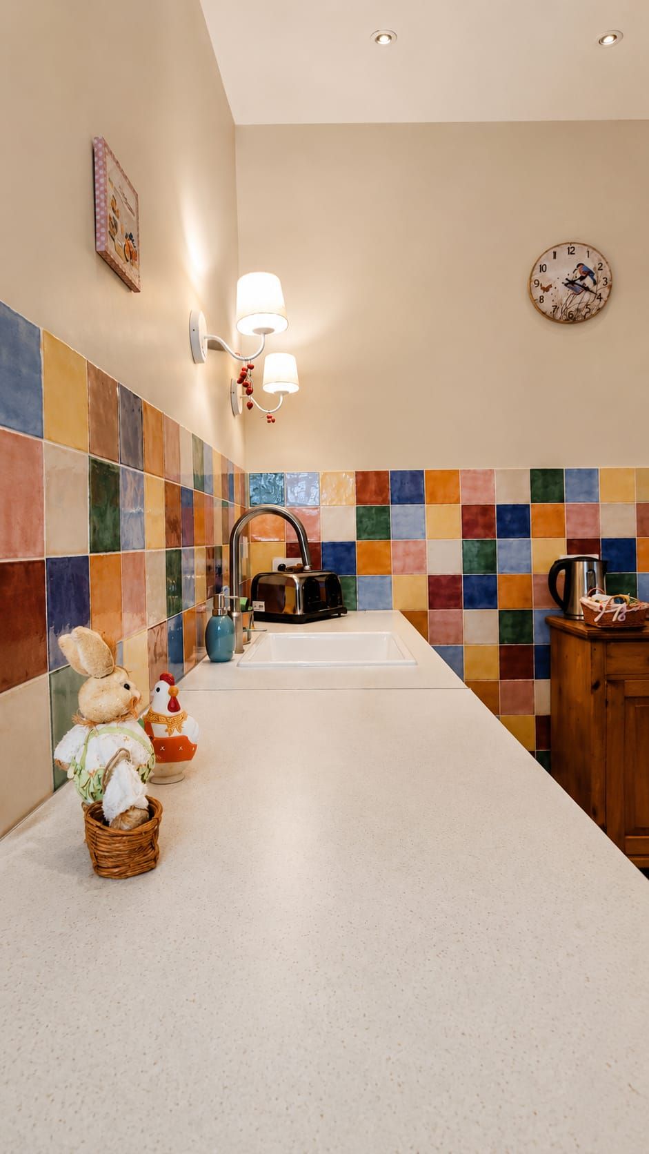 Una cocina con salpicadero de azulejos, un lavamanos, una cafetera y un armario de madera.