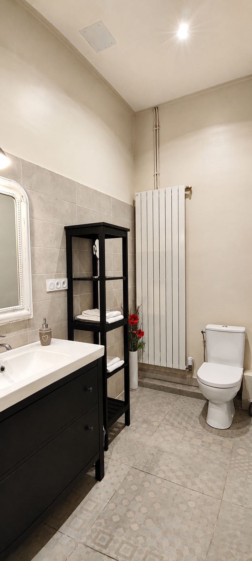 A bathroom with a white sink, black vanity, a white toilet, and a shower area.