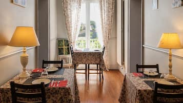 A dining area with two tables, each with a floral tablecloth, chairs, and lamps.