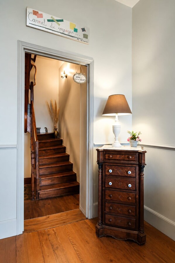 Una escalera de madera que lleva a una habitación con una lámpara y un aparador.