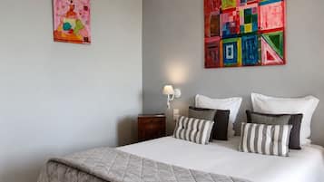 Une chambre à coucher comprenant un lit, des oreillers, une table de chevet, une lampe et deux œuvres d’art murales.