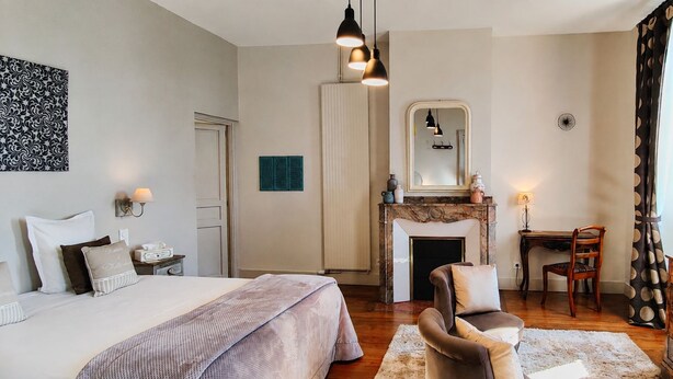 A hotel room with a bed, a desk, a chair, a television, and a fireplace. -  Maison de Maître Gentil'Home - 1699 (Fenouillet)