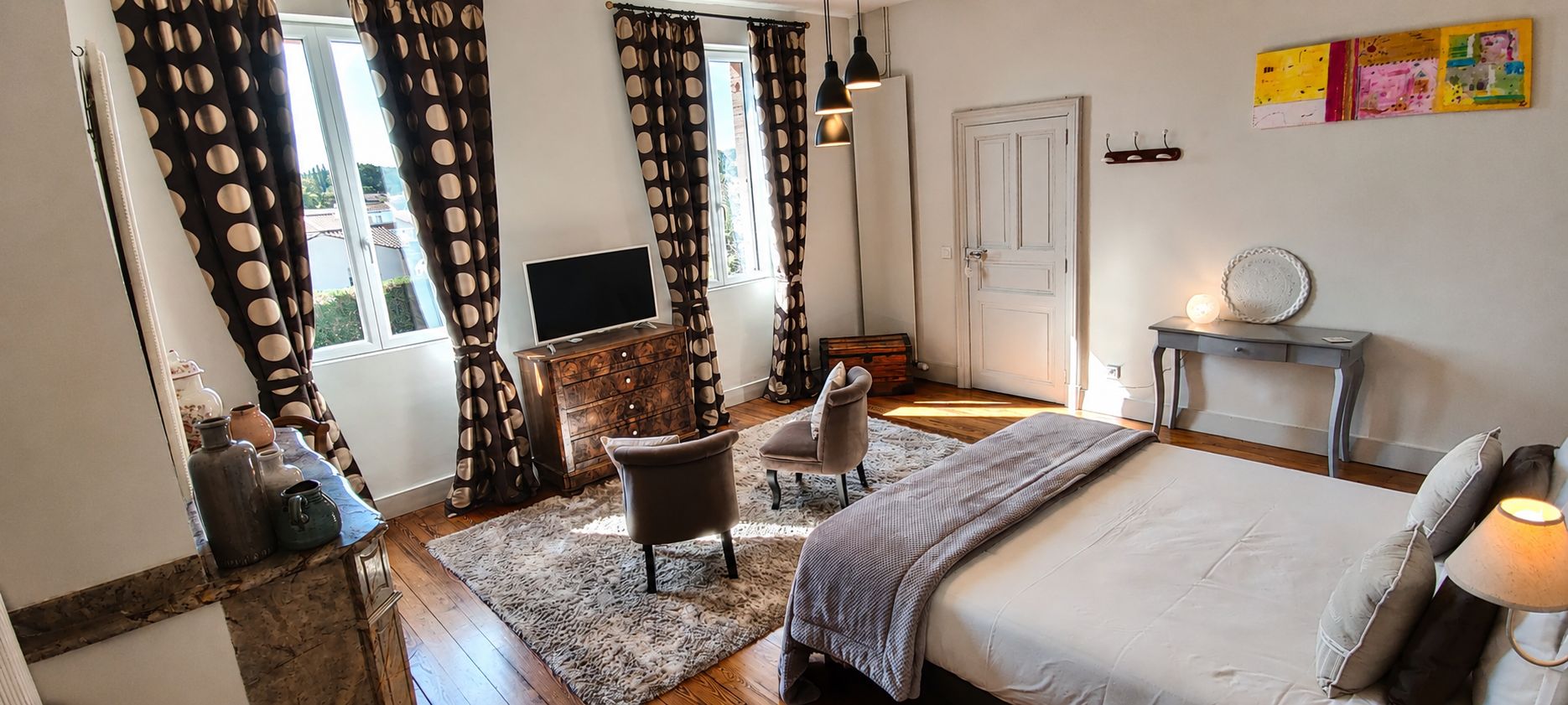 Een slaapkamer met een bed, een stoel, een bureau, een televisie en een deur.
