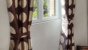A room with a window, curtains with a polka dot pattern, a wooden floor, and a brick wall. -  Maison de Maître Gentil'Home - 1699 (Fenouillet)