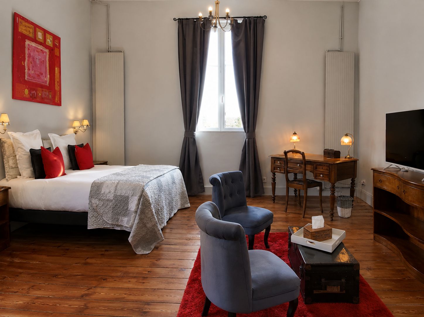 Une chambre d’hôtel avec un lit, un bureau et une chaise, une télévision et un tapis rouge.