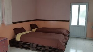 A bedroom with two beds, a wooden dresser, a door, and a television. - Full House Hostel (Yerevan)