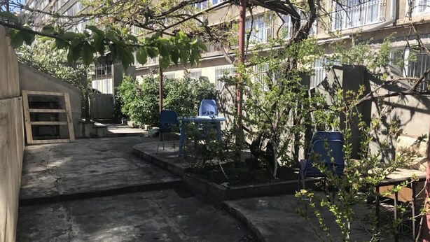 A courtyard with concrete steps leading to a small garden area, surrounded by buildings with balconies. - Full House Hostel (Yerevan)