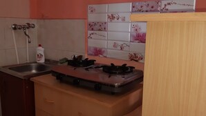A kitchen with a gas stove, a sink, and a cabinet. - Full House Hostel (Yerevan)