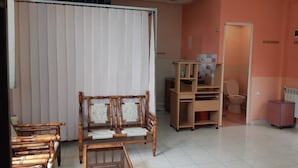 A room with a wooden chair, a small wooden table, a radiator, and a toilet. - Full House Hostel (Yerevan)