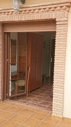 A sliding glass door leading into a room with a wooden wardrobe and a tiled floor. - Hospedería Los Cahorros (Monachil)