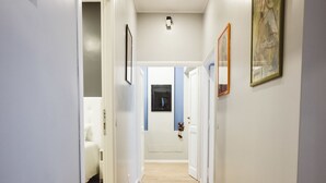 A hallway with wooden flooring, white walls, and framed artwork.
