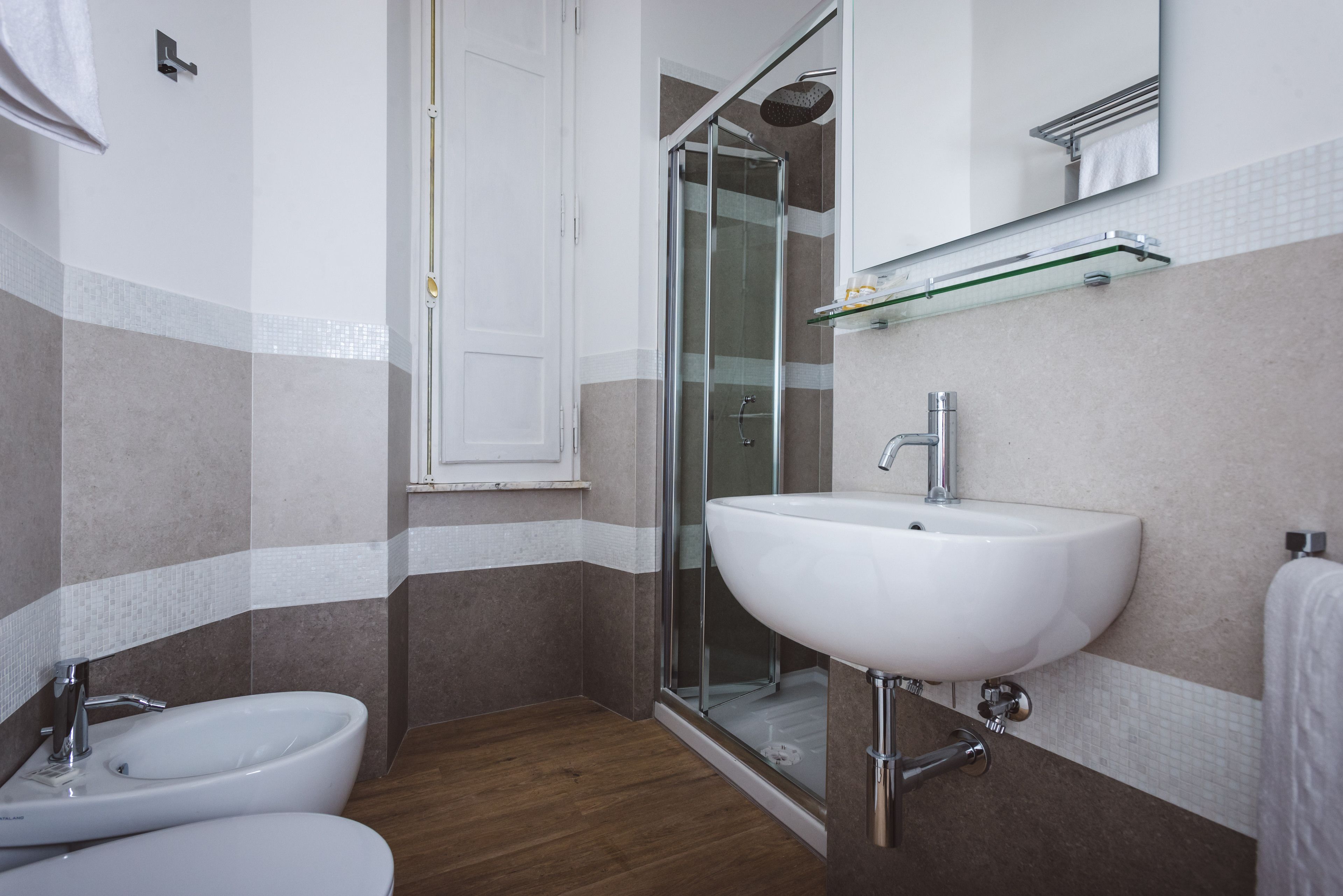 A bathroom with a shower, bidet, and sink.
