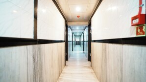 A long, narrow hallway with marble walls and a wooden floor, leading to a distant exit. - Hotel Kings Palace (Mumbai)