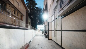 A corridor with tiled walls and a patterned floor, leading to a building entrance. - Hotel Kings Palace (Mumbai)