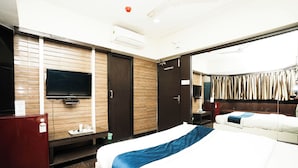 A hotel room with a bed, a TV, a desk, and a wardrobe. - Hotel Kings Palace (Mumbai)