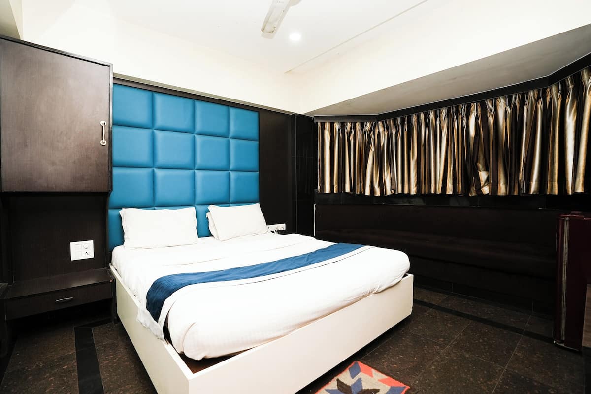 Una habitación de hotel moderna con una cama grande, un armario y una ventana con cortinas.