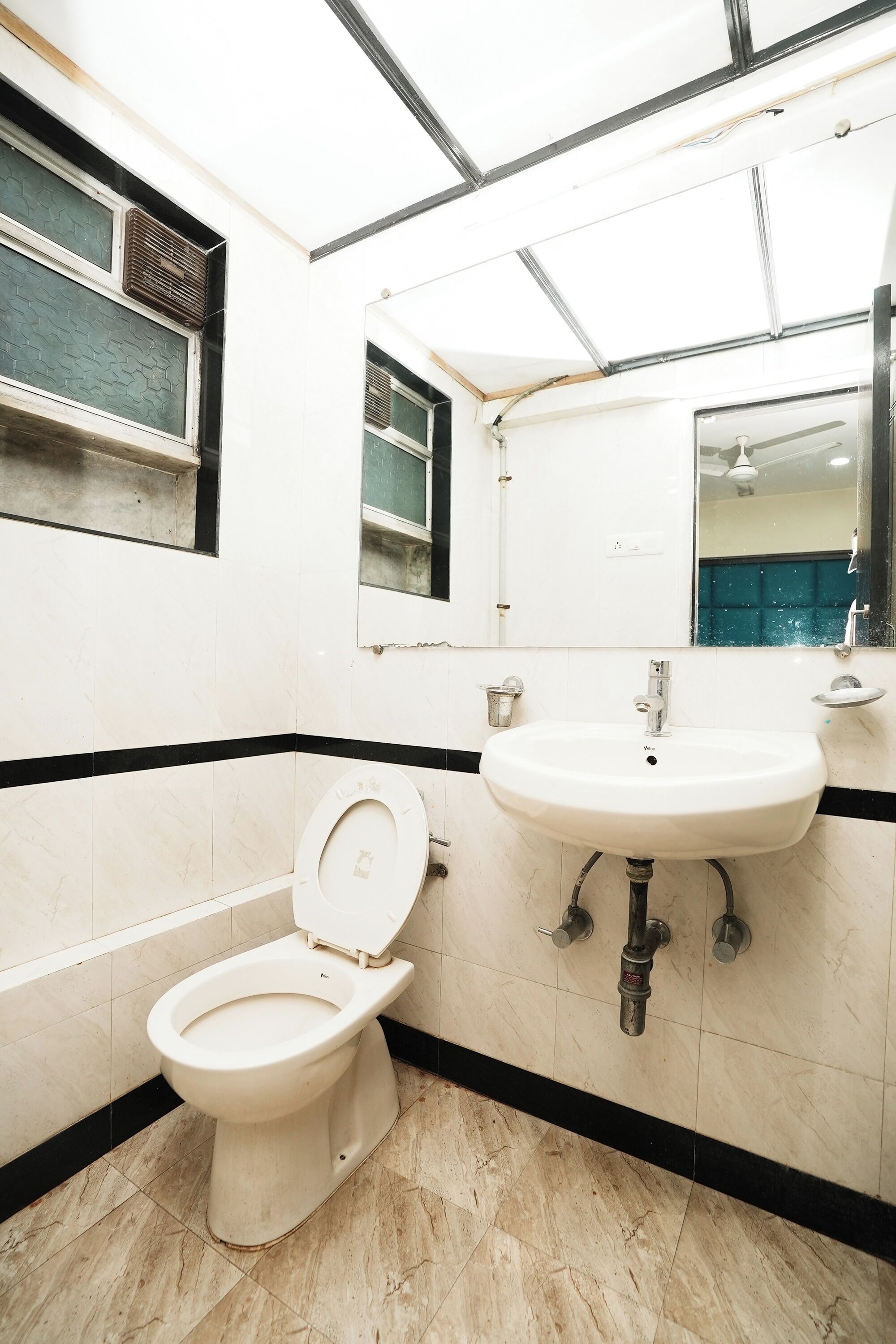A bathroom with a toilet, sink, and mirror.