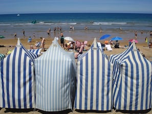 Striped beach umbrellas with numbers 911, 912, and 990. - Pensión Zarauz Playa (Zarautz)