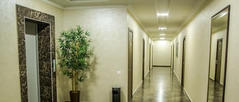 A hallway with marble flooring, a potted plant, and framed mirrors on the walls.