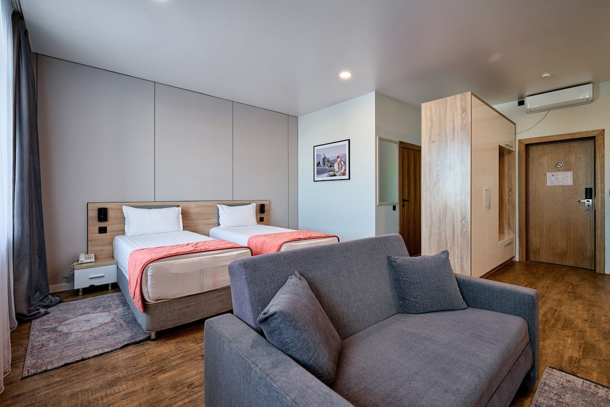 Une chambre d’hôtel moderne équipée d’un grand lit, d’un canapé, d’un bureau et d’une armoire.
