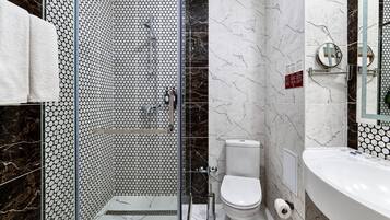 A modern bathroom with a glass shower enclosure, a toilet, and a sink.