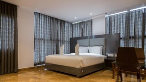 Una habitación de hotel moderna con una cama grande, un escritorio y una silla.